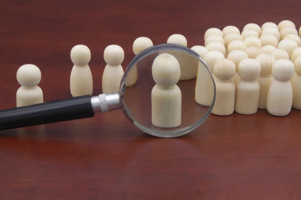 Several chess pieces on a table with a magnifying glass pointed at one of them.