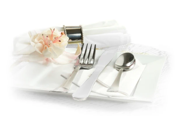 a silver spoon, fork and knife on a plate and adorned with a flower